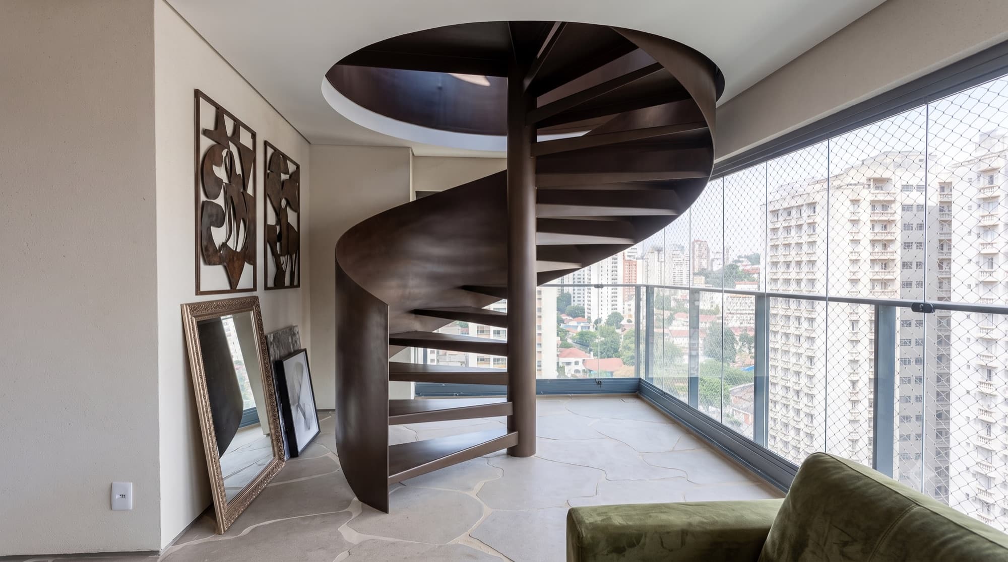 Escada helicoidal em aço escuro, com curva contínua, na varanda de um apartamento