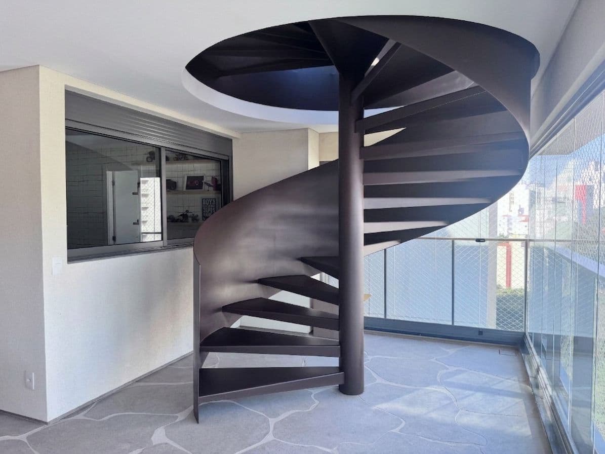 Escada caracol metálica com guarda-corpo curvo, projeto da Escadas MV para a cliente Gabriela, em Perdizes, São Paulo.