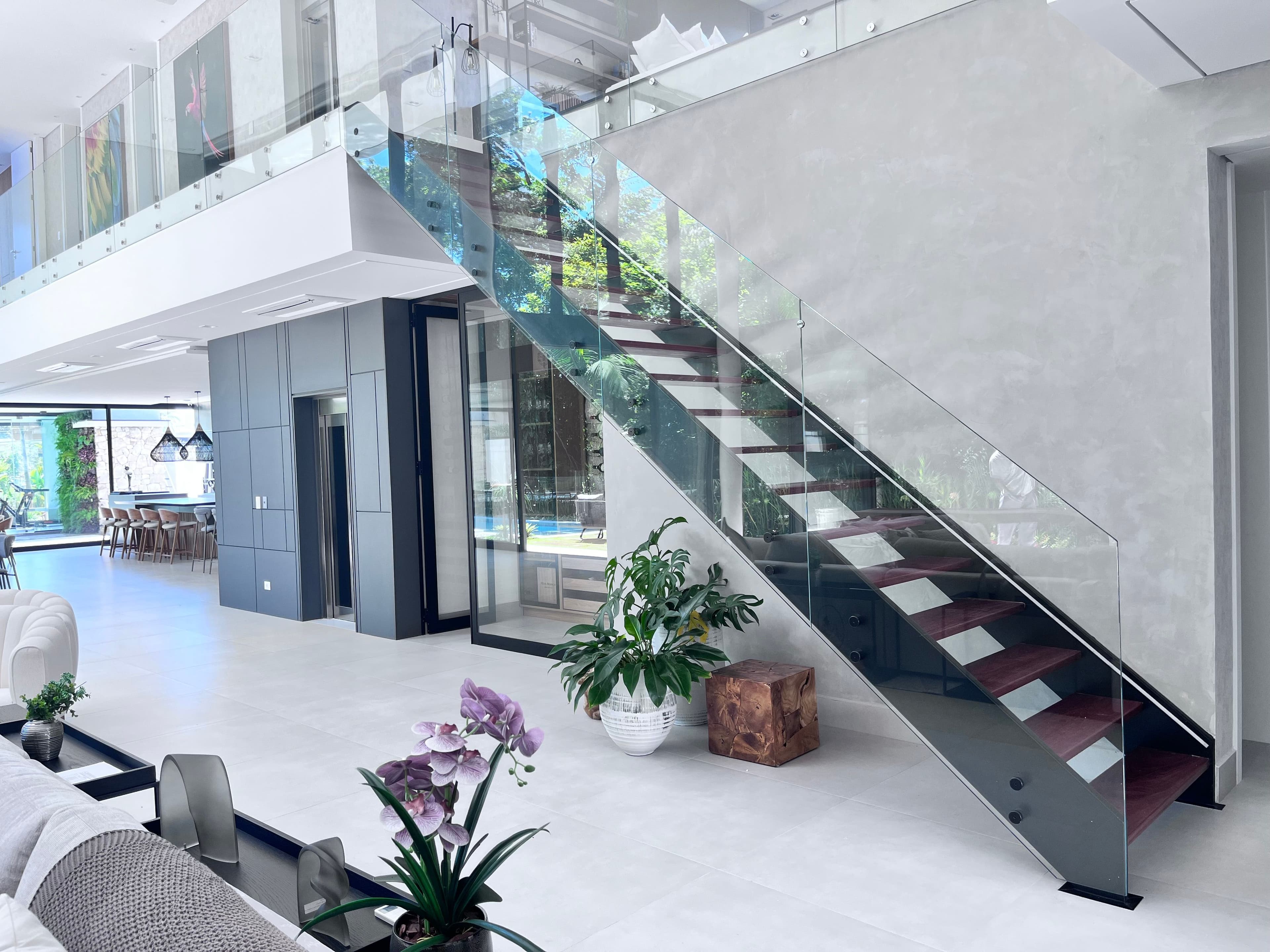 Duas escadas retas entre vigas, sobrepostas, com degraus em madeira jatobá e guarda-corpo em vidro fixado com botões de aço inox, projeto da Escadas MV em parceria com a Melro Arquitetura, na Riviera de São Lourenço, Bertioga-SP.